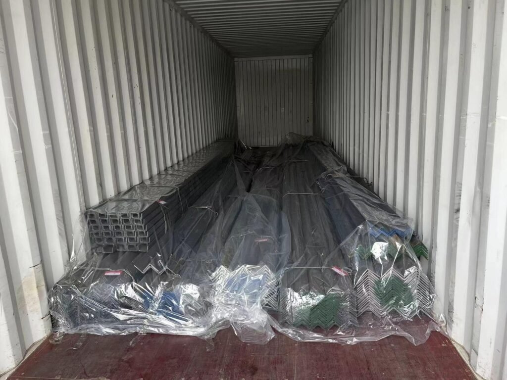 Bundles of structural angle steel being loaded into a shipping container at the Ruicheng Steel warehouse facility for export.